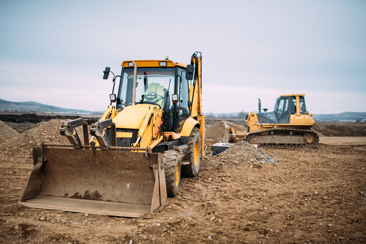 a group of construction vehicles in a dirt field